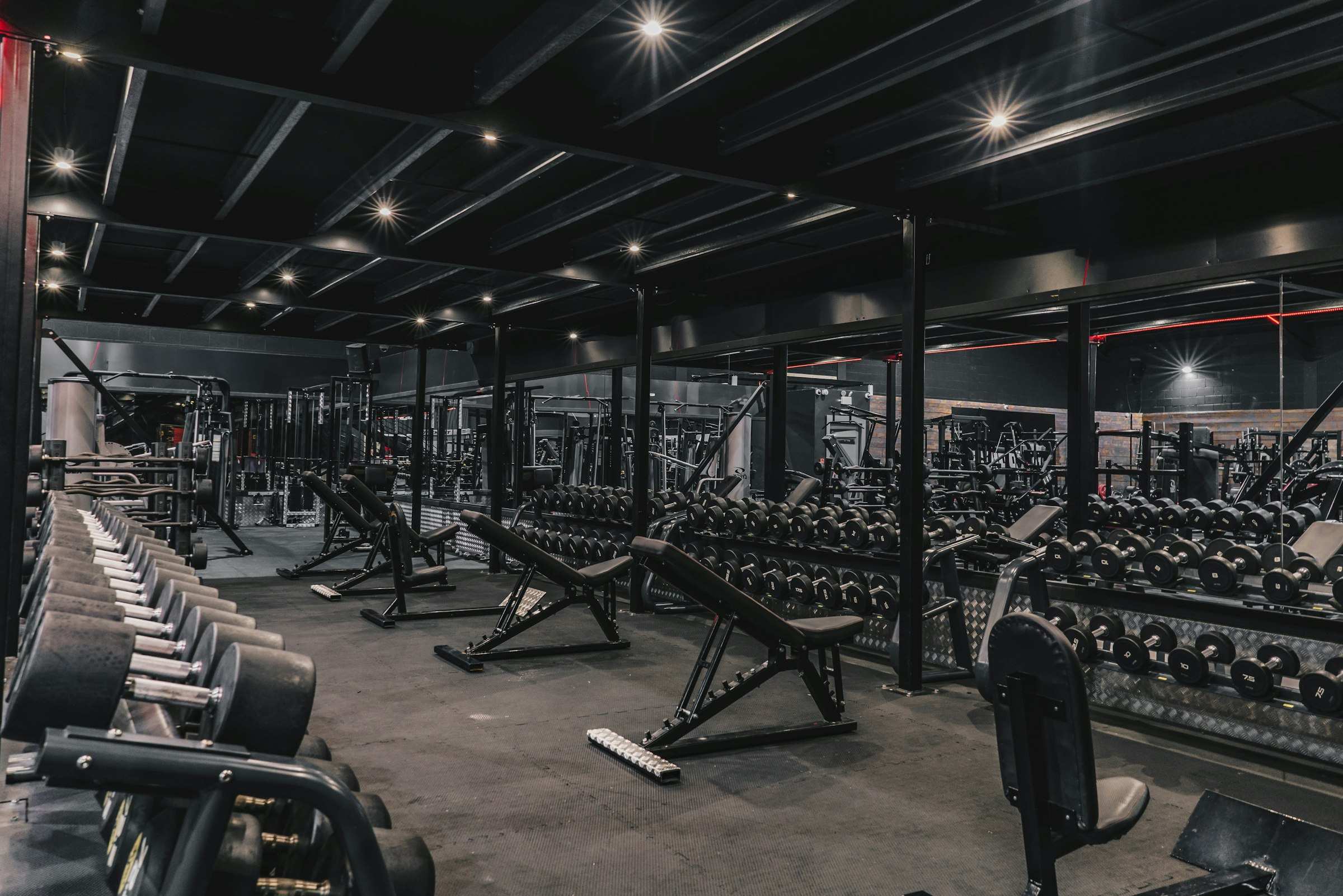 A gym floor of assembled racks, benches and dumbbell stands