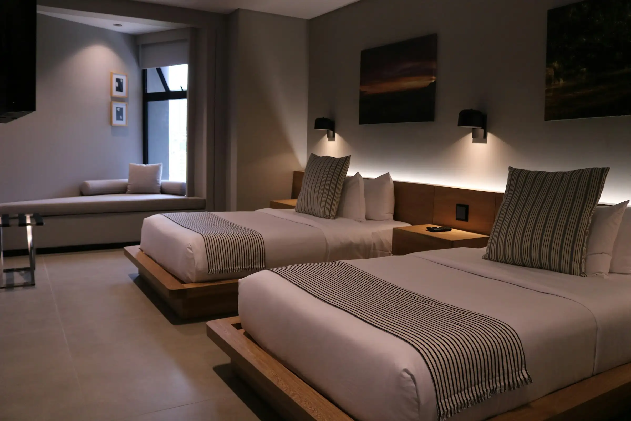 A hotel guest room with two assembled beds, a couch and case goods